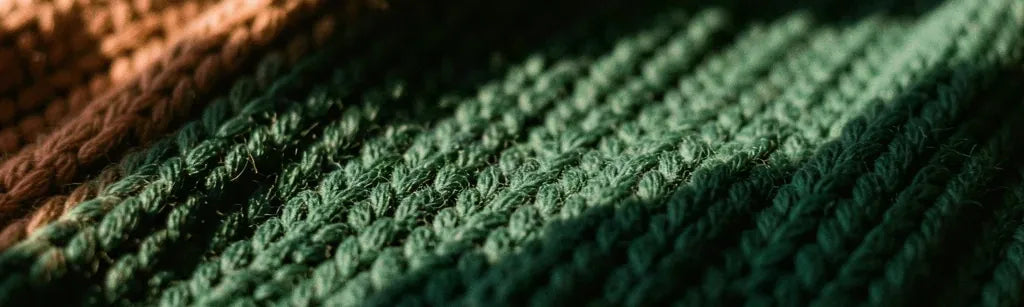 Close-up of knitted cotton in forest green and rust, in warm side light